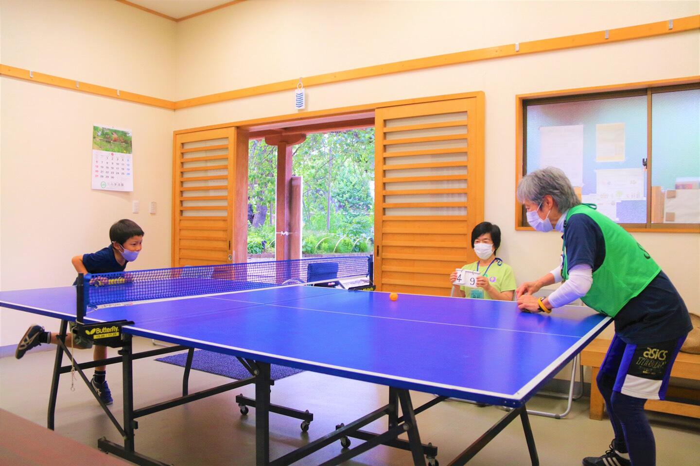卓球台とピンポン玉を使って、筒を両手に持った男の子と増田理事長が対決している様子