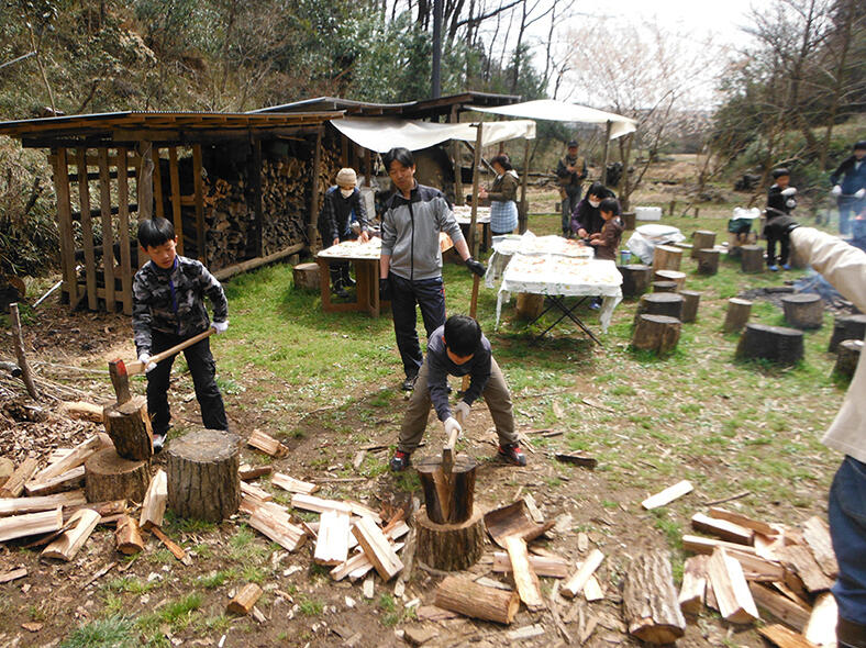 斧を持って薪割りをしている子どもたちや石窯を使って料理をしている親子