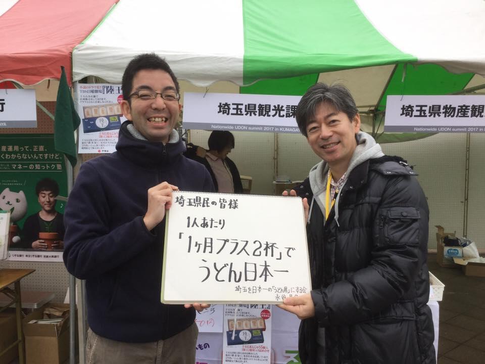 「１人あたり1か月プラス２杯で　うどん日本一」と書かれた紙を持つ齊藤さんと永谷さん