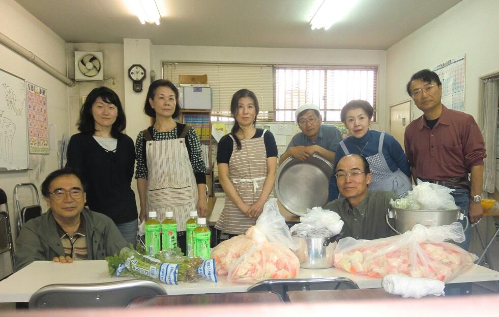 調理場で江藤さんと宮北会のメンバーが記念撮影をしている