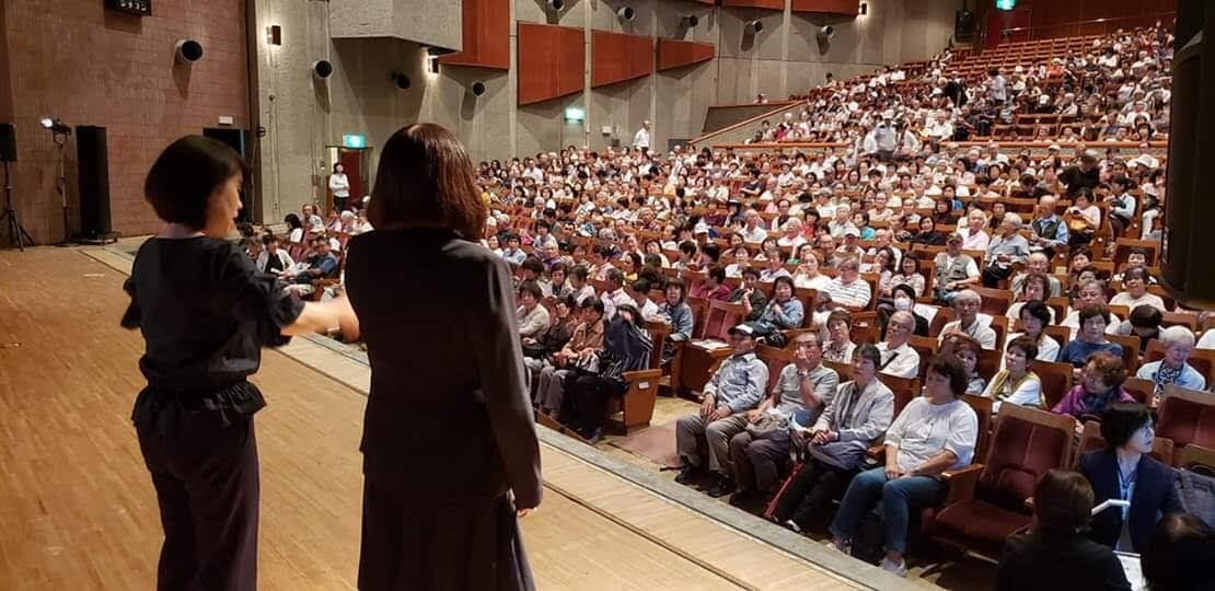 大勢の参加者の前で司会をする川名さん。