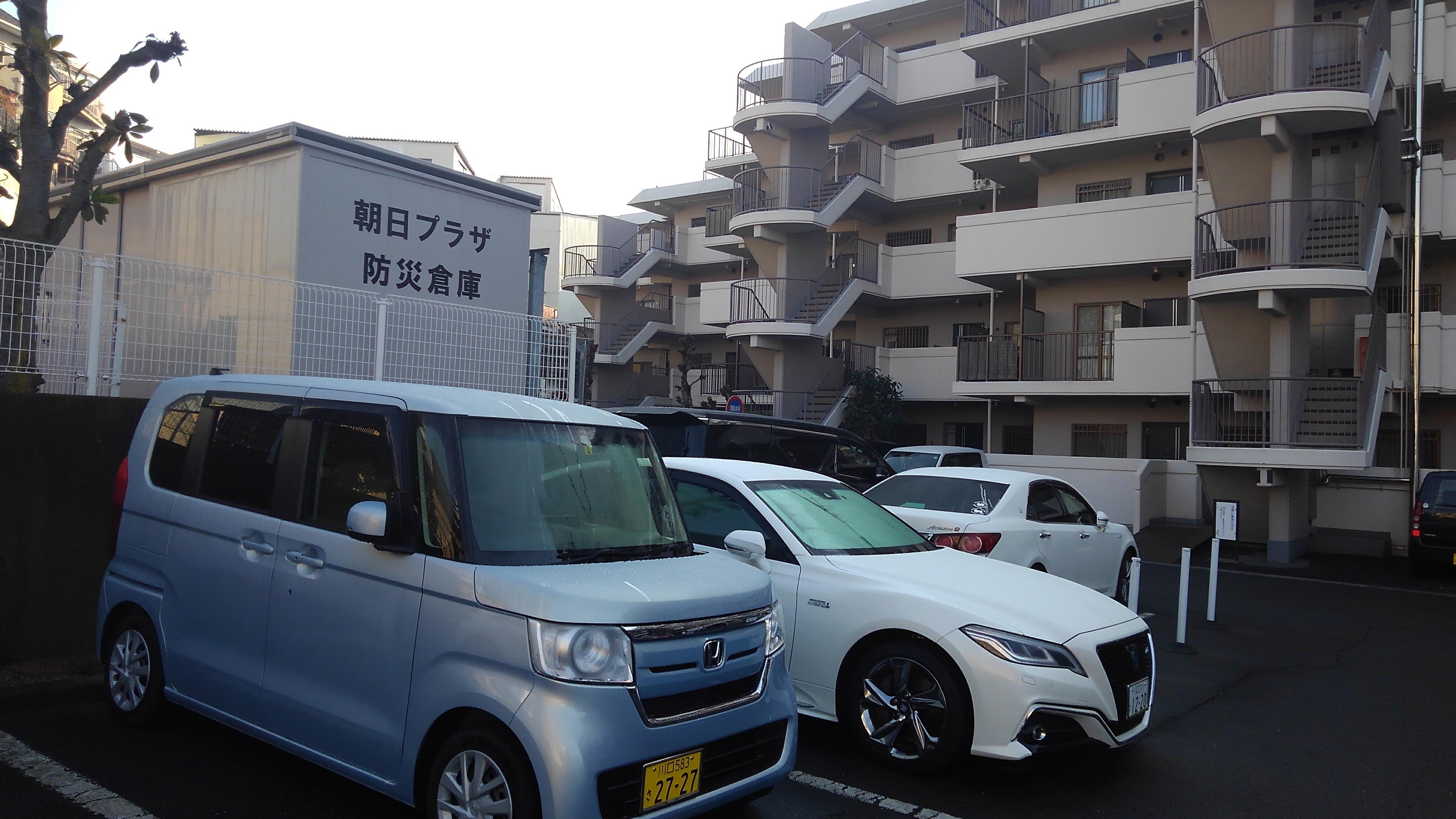 マンション敷地内の駐車場近くに朝日プラザ防災倉庫と書かれたコンテナ