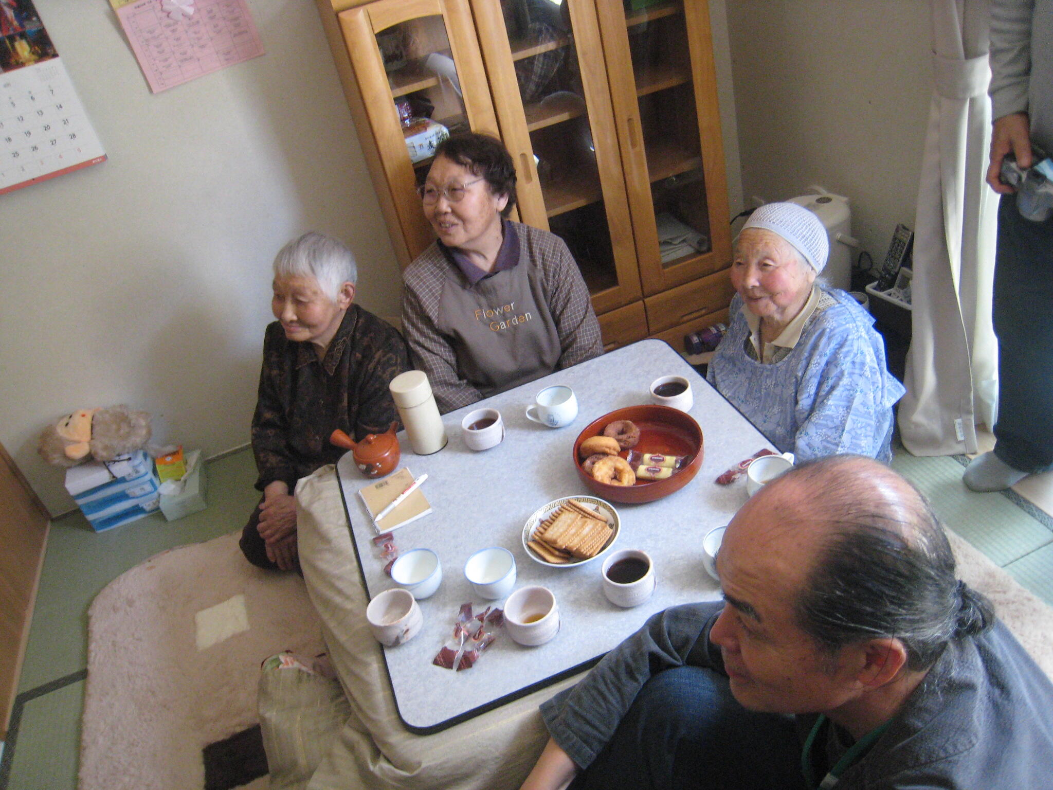 コタツの周りに女性3人と江藤さんが座って、同じ方向を見ている
