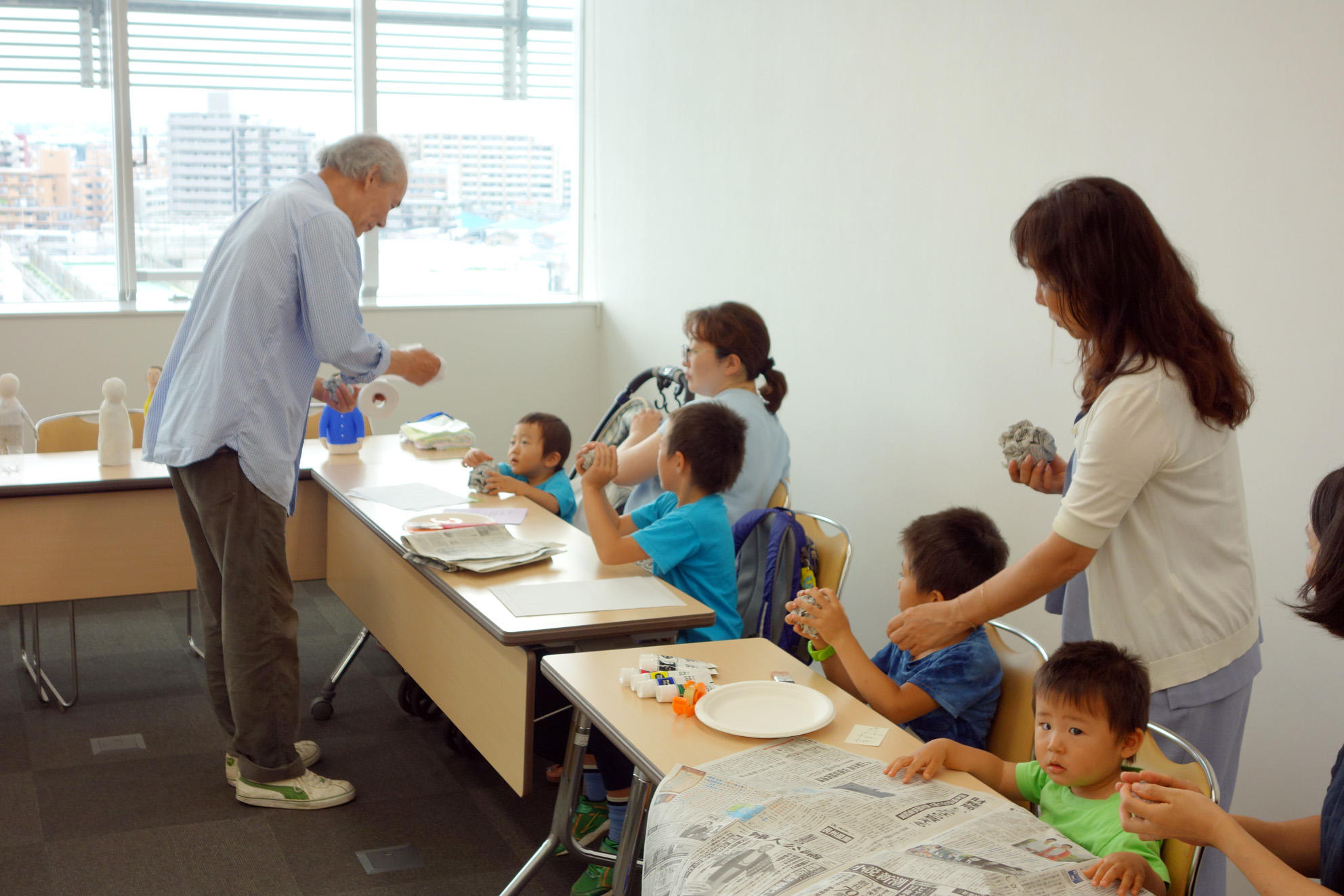 人形作家の茅木さんが２組の親子に机を挟んで教える画像